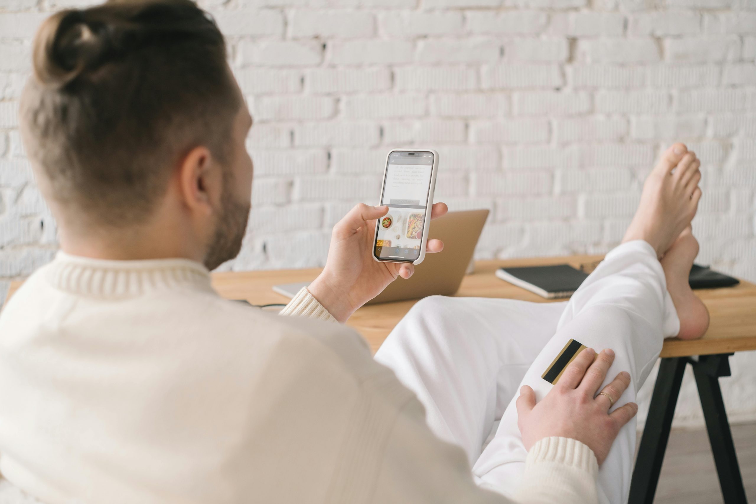 man browsing his smartphone with his feet resting on a desk
