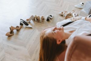 woman lying on a couch beside an array of high-heeled shoes