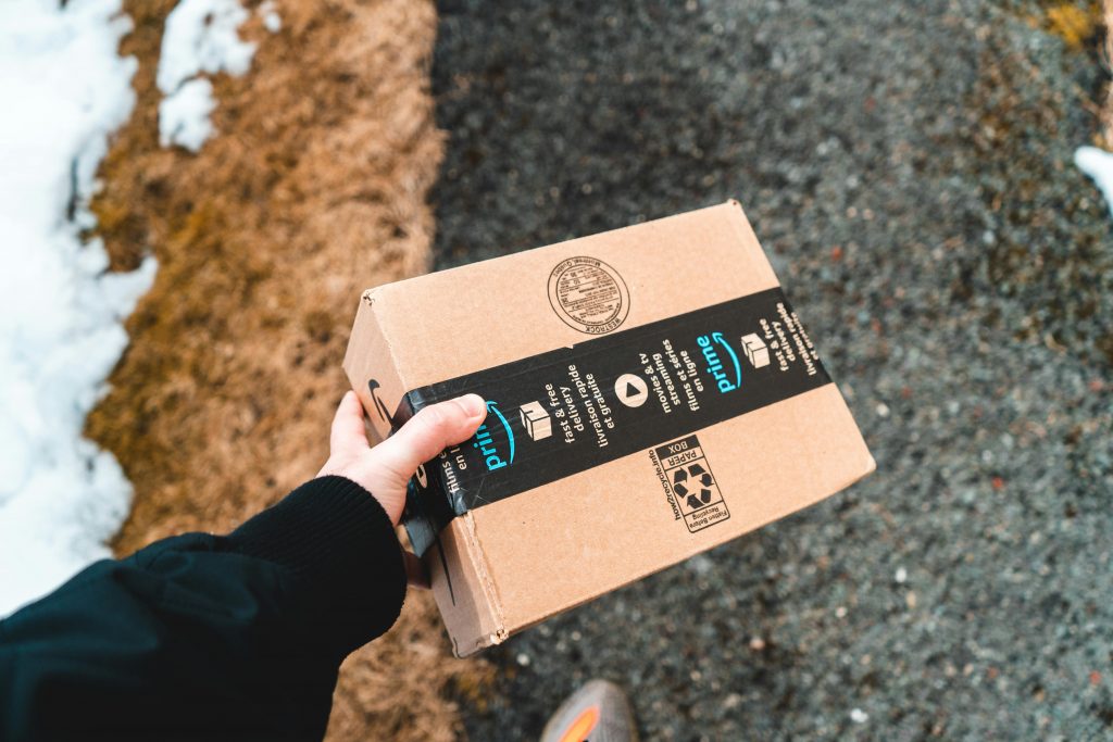 close-up of a hand holding a cardboard box with Amazon packaging tape