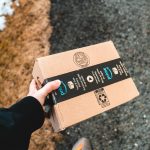 close-up of a hand holding a cardboard box with Amazon packaging tape